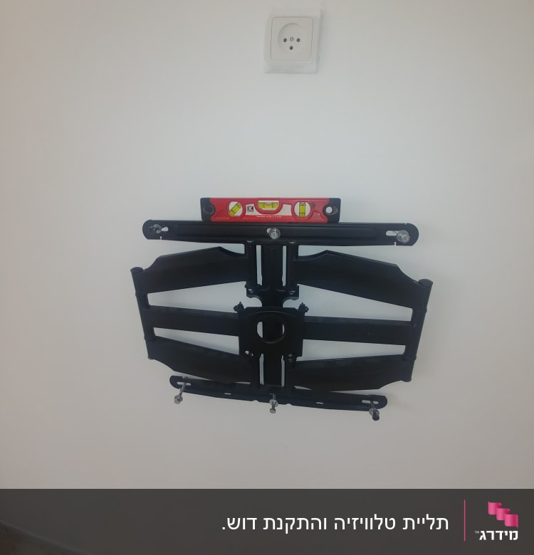 מתקן תלייה לטלוויזיה עם פלס על קיר לבן